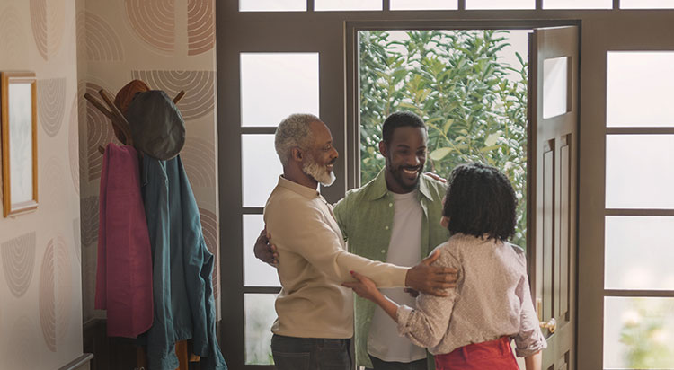 Man greeting his family in the doorway of his home